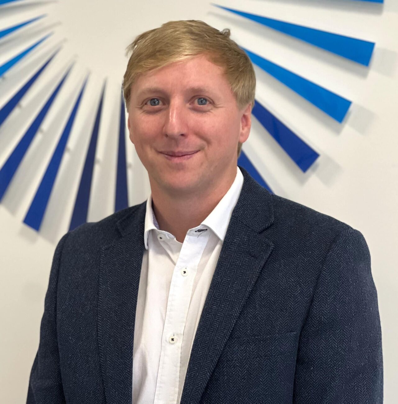 Image of James Tate, at the Tadek office, smiling at the camera